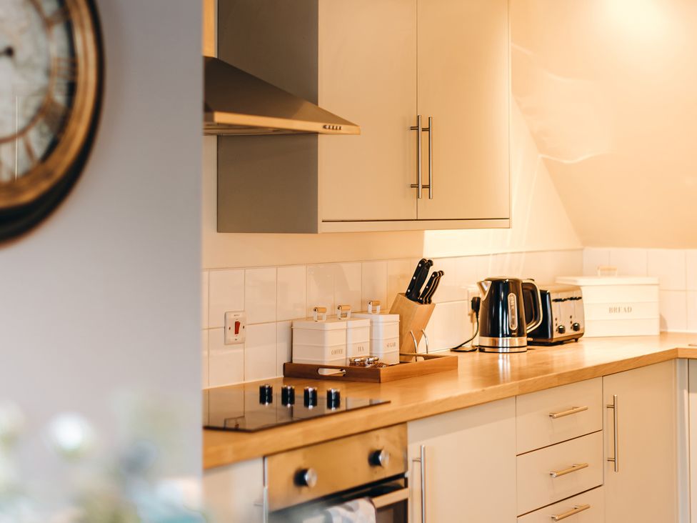 A kitchen countertop with a stovetop a kettle toaster knife block and storage containers at The Pheasant Apartment Neenton