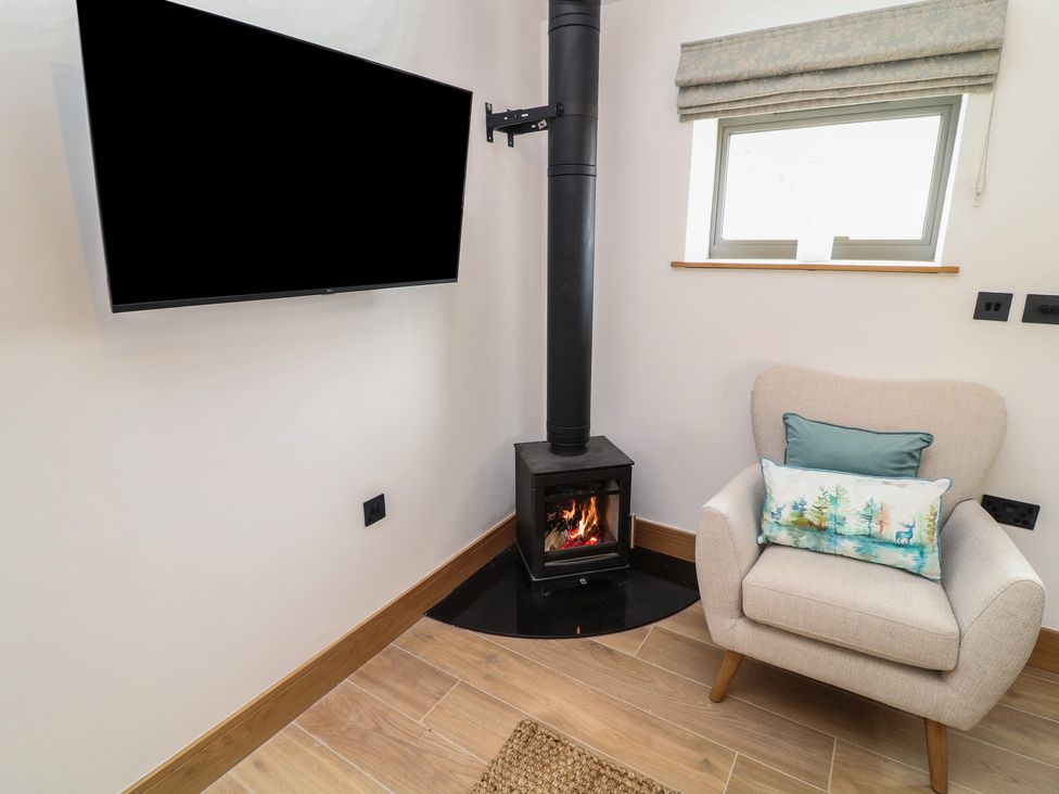 A snug with a television and a wood stove at Tawny Barn in Woodhall Spa