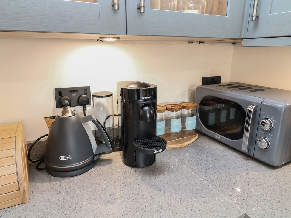 A kitchen countertop with appliances including a kettle, coffee machine, and microwave at Tawny Barn Woodhall Spa