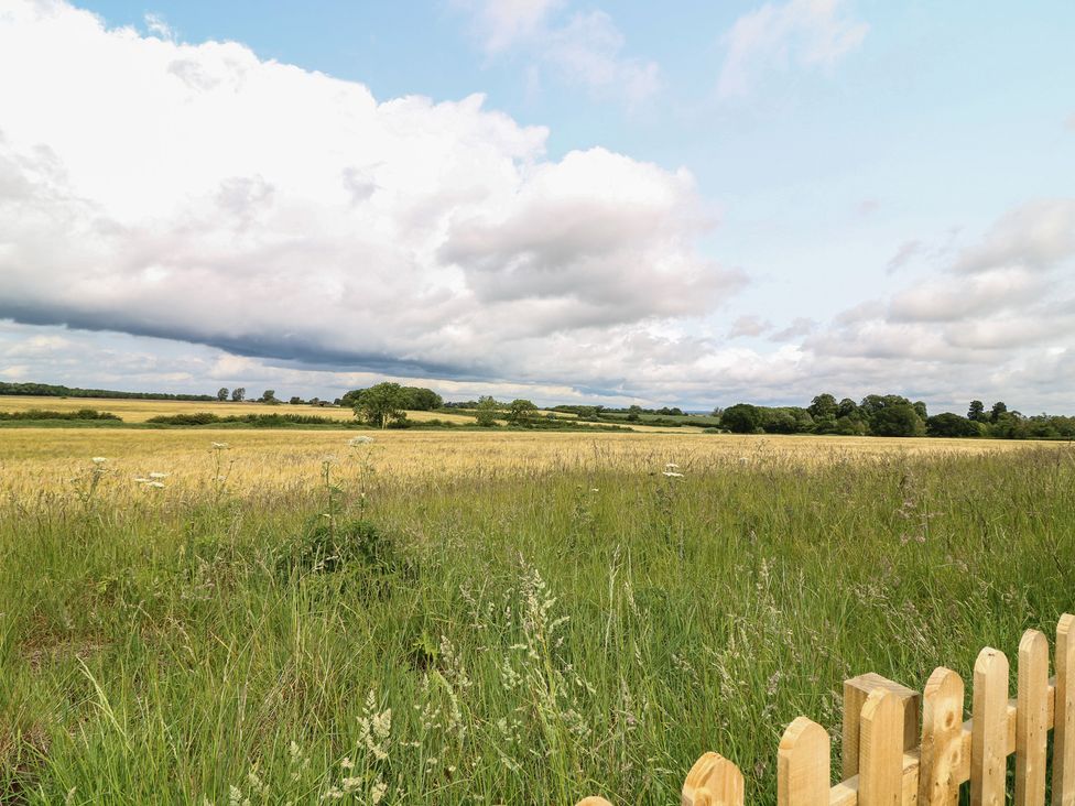 A grassy field with a wooden fence at Tawny Barn in Woodhall Spa