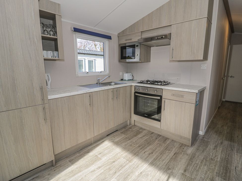 A kitchen with cabinets, sink, stove, oven, and microwave at Lido Gold 120 in Prestatyn