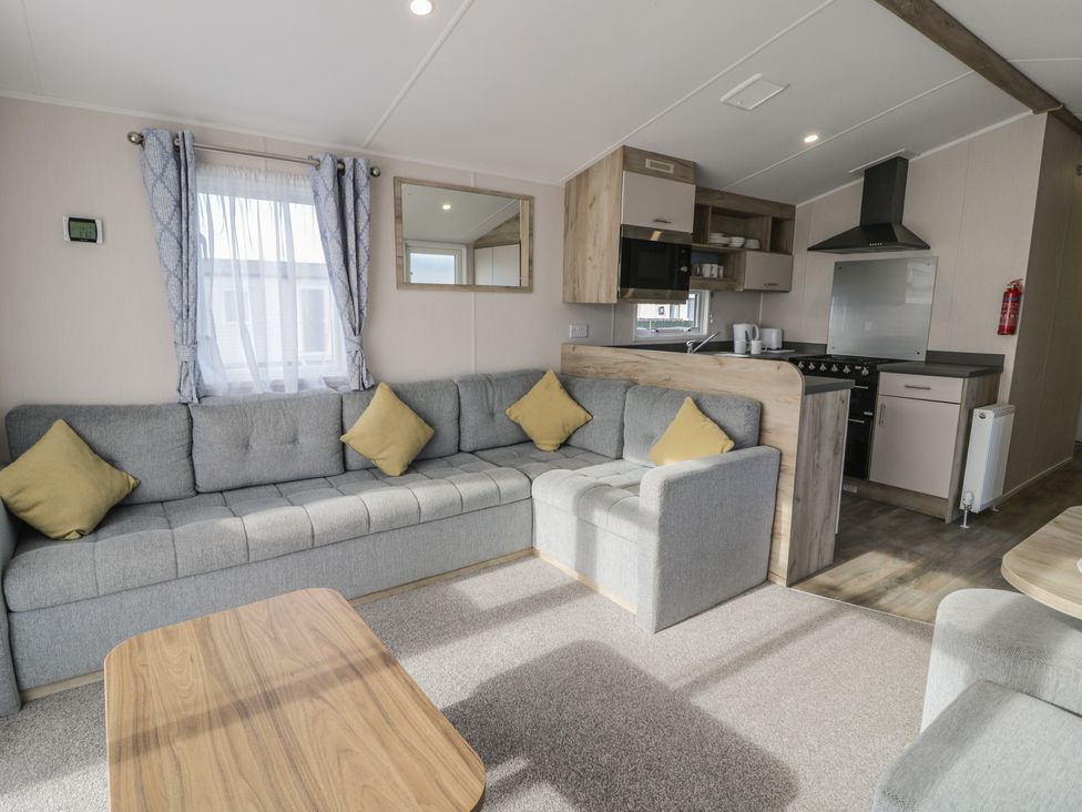 A living room with a sofa and kitchen area at Lido Gold 273 in Prestatyn