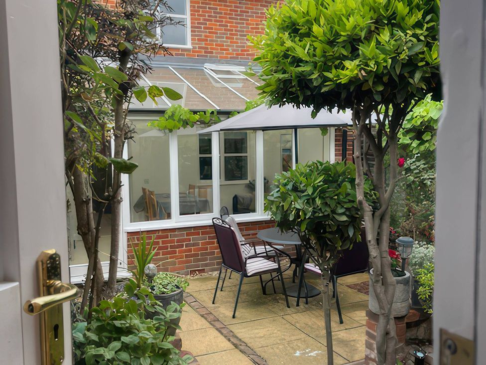A garden with a table and chairs under an umbrella at Bay Tree Cottage, Peasenhall