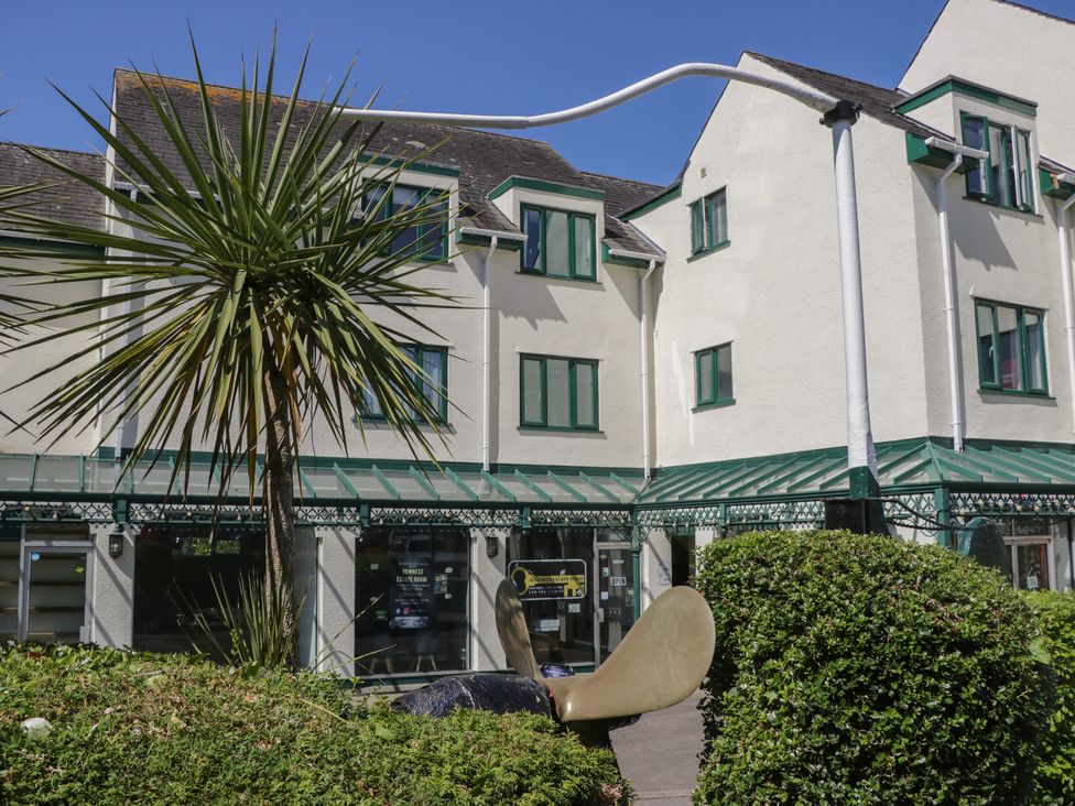 A building with green window frames and a glass awning with a palm tree and a large metal sculpture in front at Eve's Attic in Bowness-On-Windermere
