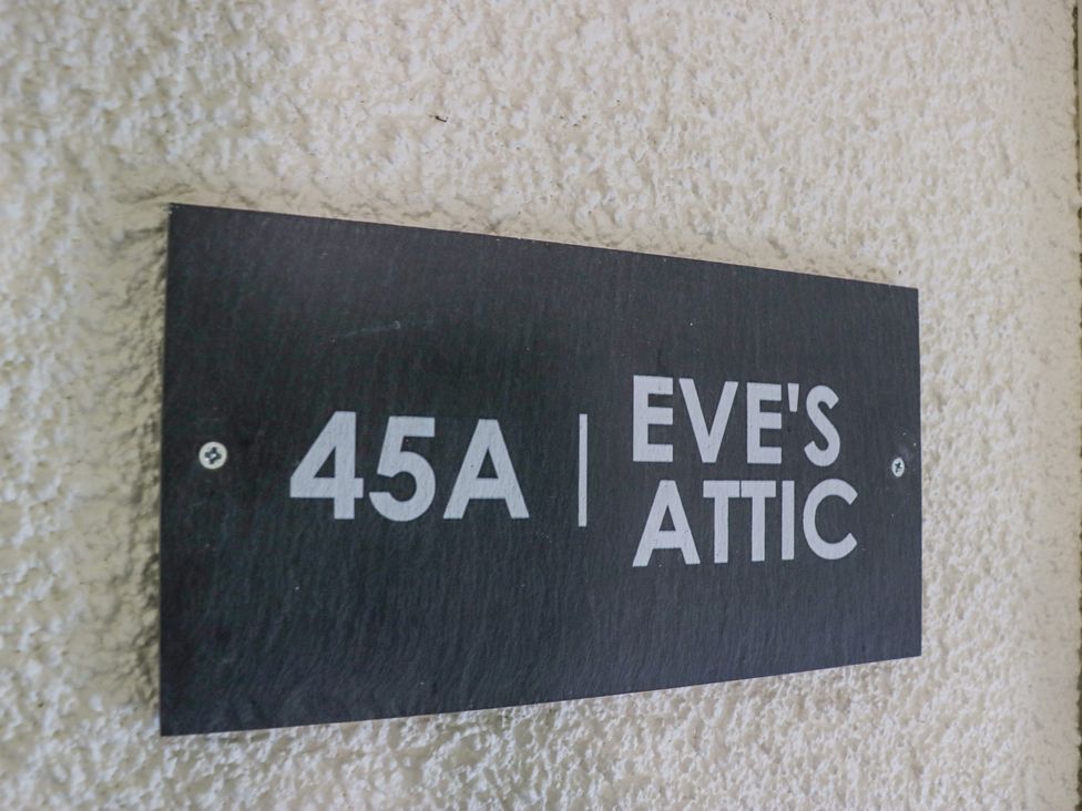 A black rectangular sign with white text 45A Eve's Attic mounted on a textured wall at Eve's Attic in Bowness-On-Windermere