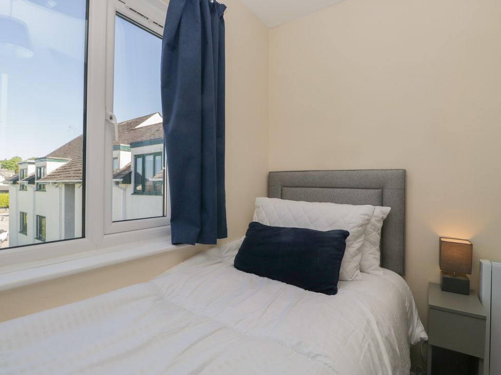 A bedroom with a single bed a blue cushion and bedside table with a lamp at Eves Attic in Bowness-On-Windermere