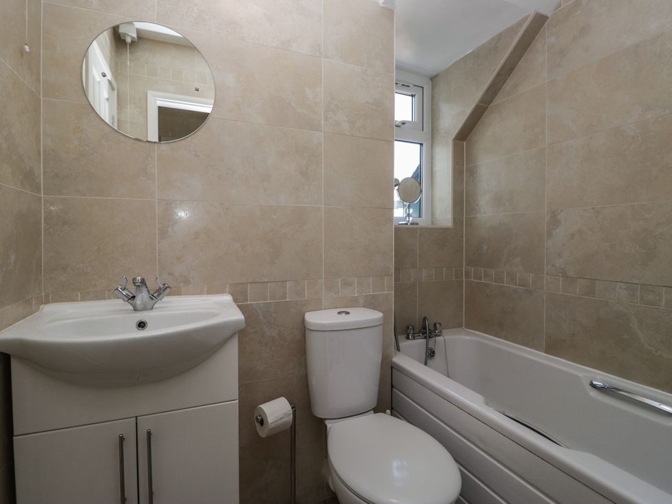 A bathroom with a sink and cabinet toilet and bathtub with a window above at Eves Attic in Bowness-On-Windermere