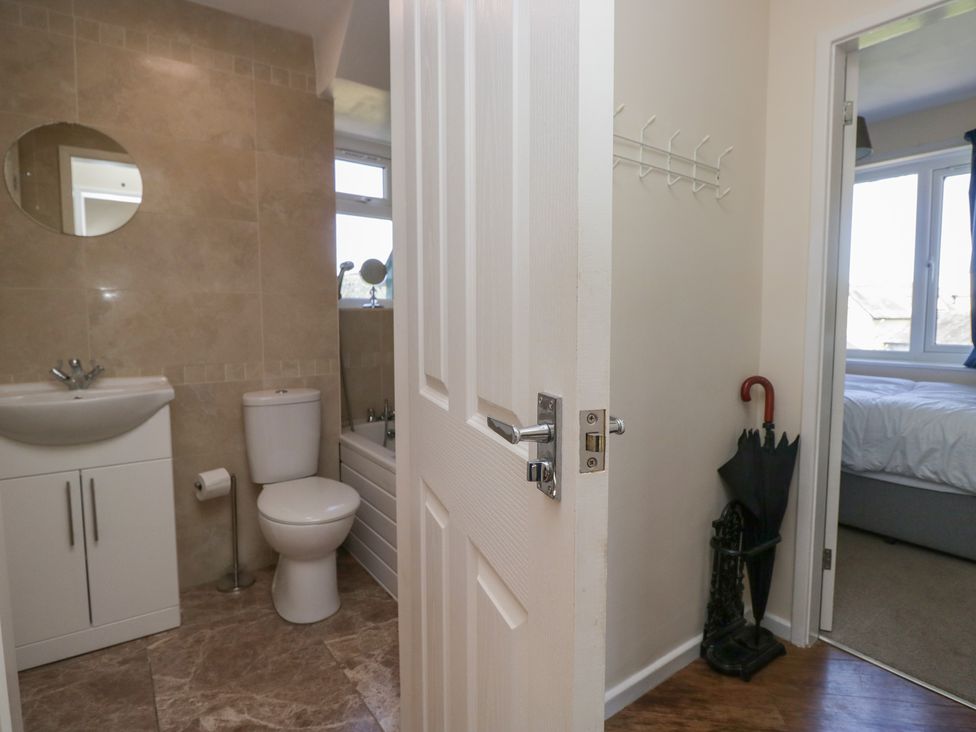A bathroom with a toilet sink and bathtub next to a hallway with an umbrella stand near a bedroom at Eves Attic in Bowness-On-Windermere