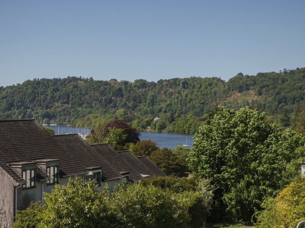 Roofs of houses with trees and a lake behind hills at Eves Attic in Bowness-On-Windermere