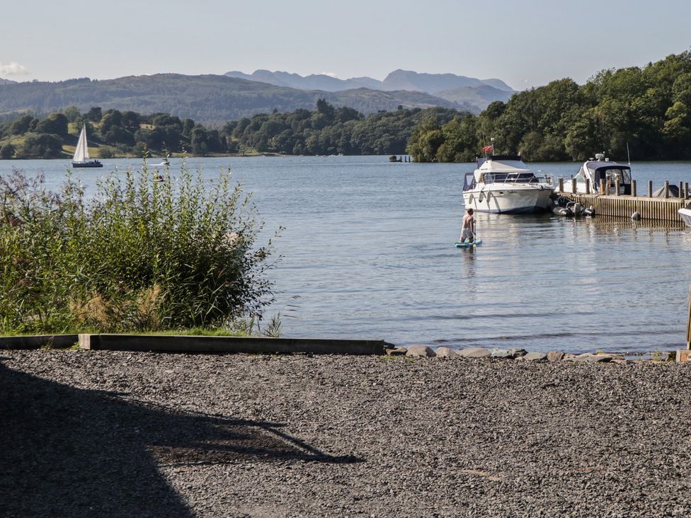 A person on a paddleboard on a lake near boats and a gravel shore at Eve's Attic in Bowness-On-Windermere