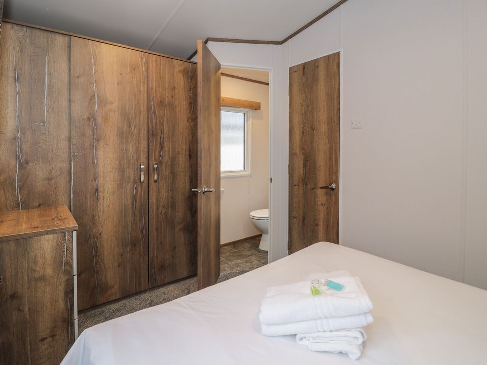 A bedroom with a wardrobe and towels on the bed at Woodlands Gold (WO40) in Ruthin