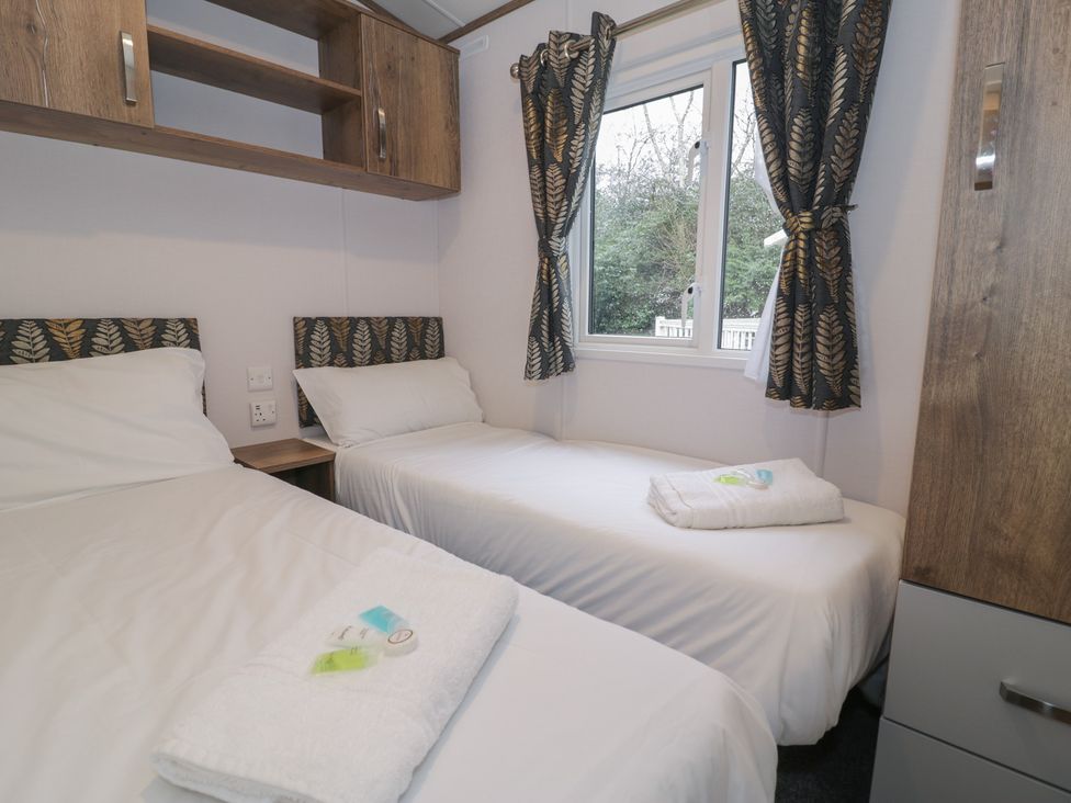 A bedroom with a double bed, single bed and window at Woodlands Gold (WO40) in Ruthin