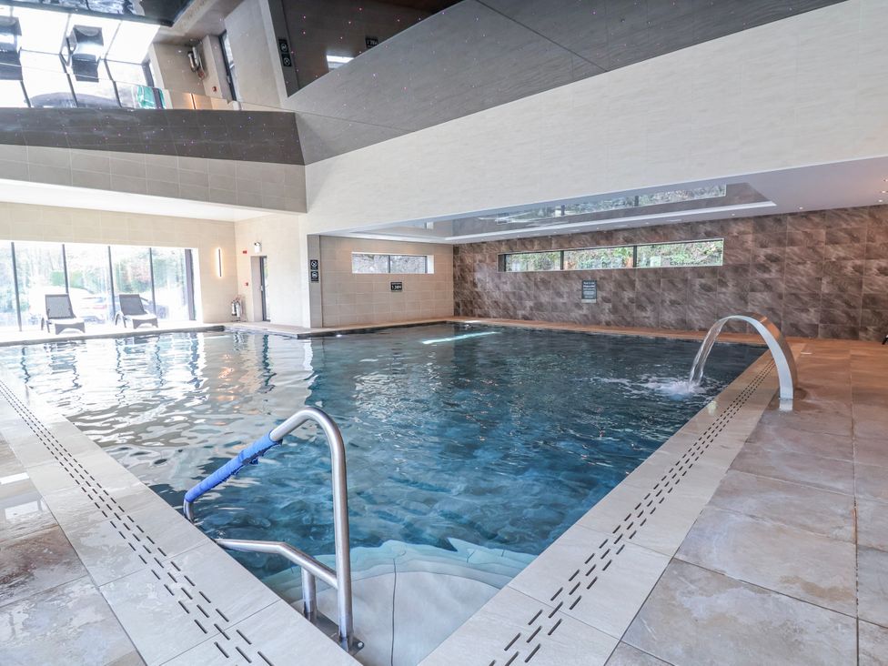 A swimming pool area with a waterfall feature at Woodlands Gold (WO40) Ruthin