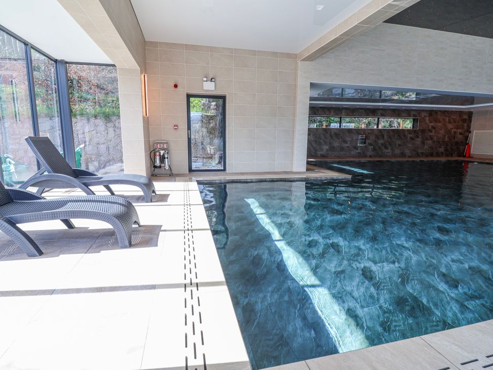 An indoor pool area with lounge chairs at Woodlands Gold (WO40) in Ruthin