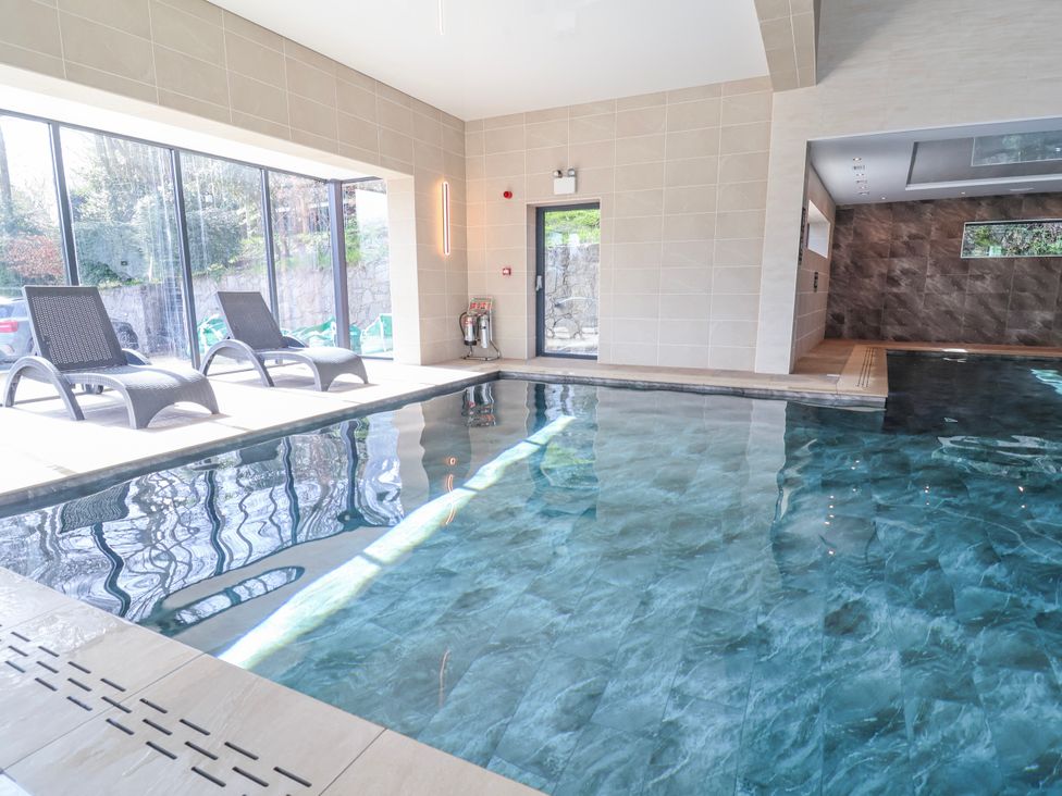 An indoor pool area with deck chairs and large windows at Woodlands Gold (WO40) in Ruthin