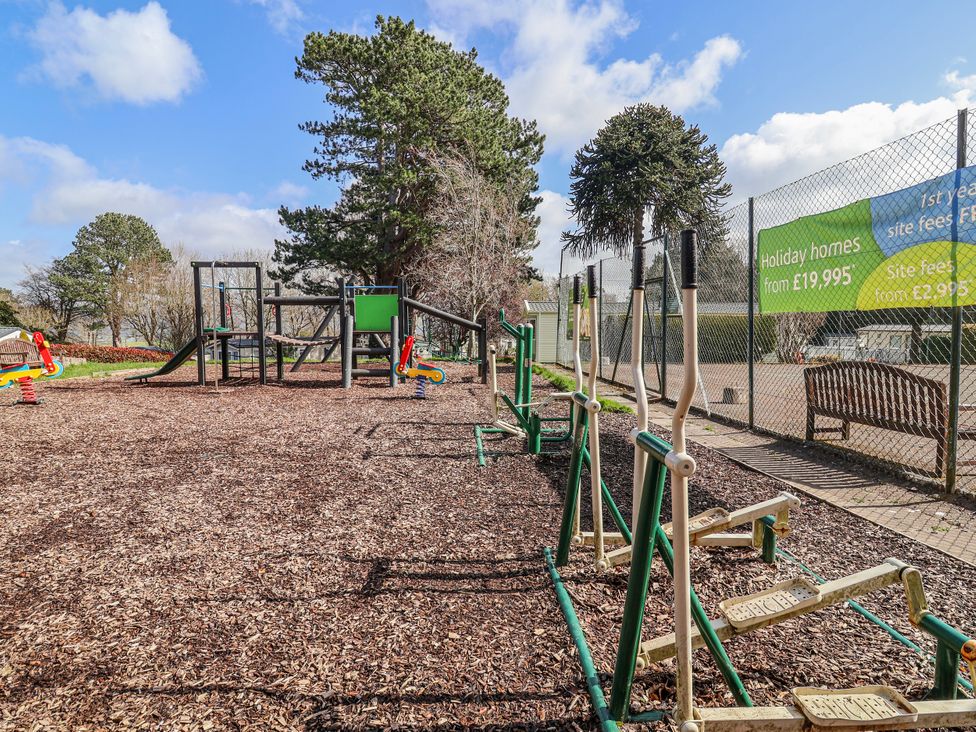 An outdoor play area with playground equipment and fitness stations at Woodlands Gold (WO40) Ruthin
