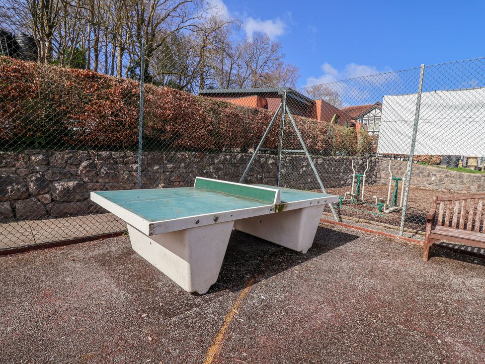A table tennis table and a bench in an outdoor area at Woodlands Gold (WO40) Ruthin