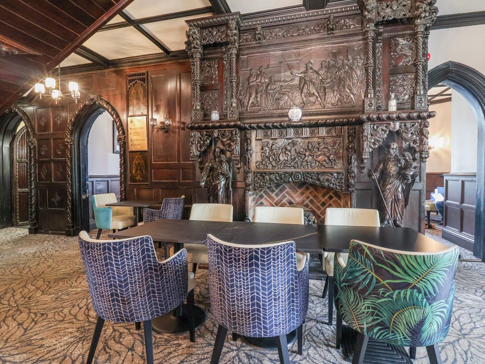 A dining room with a wooden fireplace and several chairs at Woodlands Gold (WO40) in Ruthin