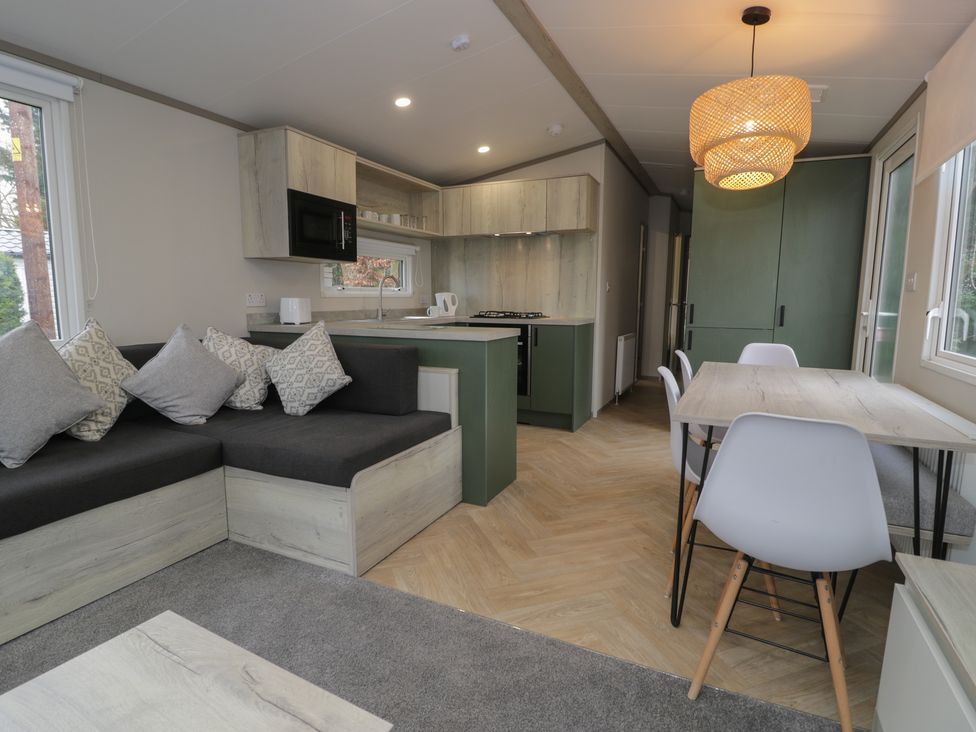 A living room with a sofa and dining area at Woodlands Gold (WO06) in Ruthin