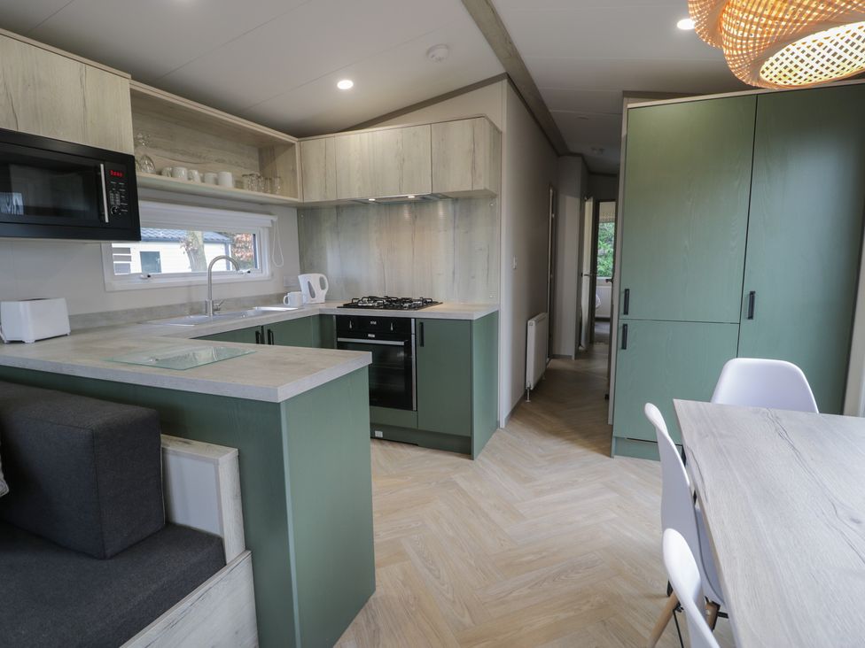 A kitchen with appliances and seating at Woodlands Gold (WO06) in Ruthin