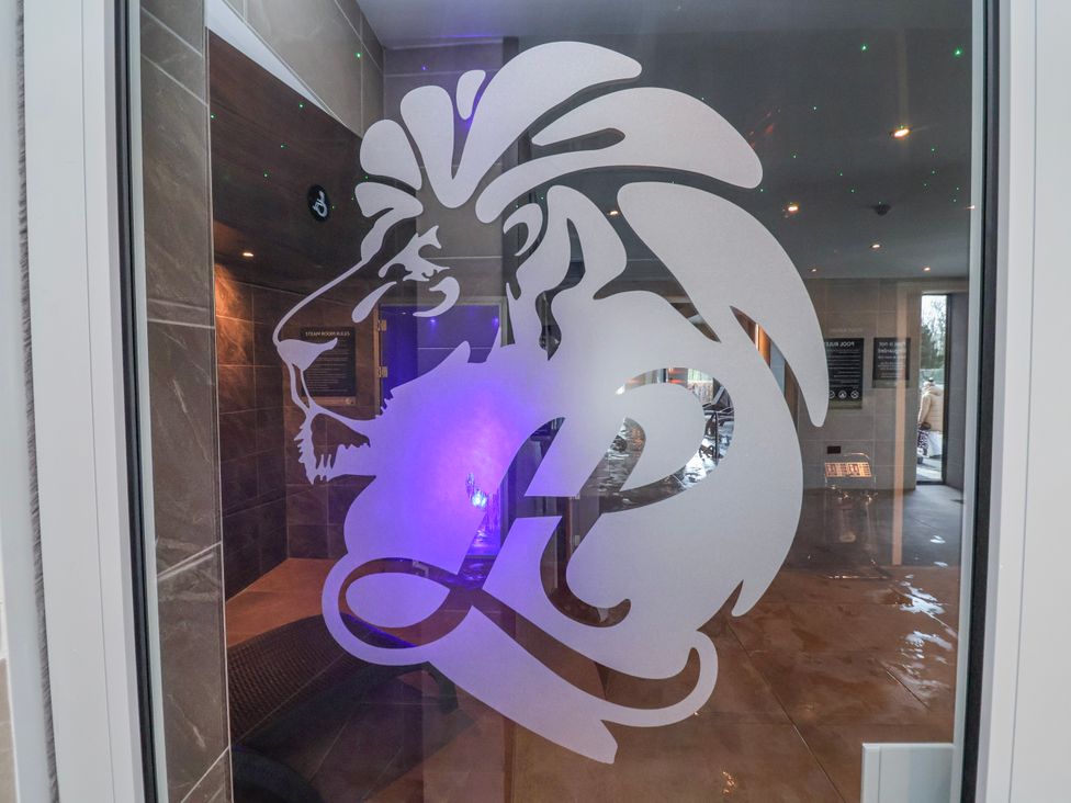 A glass door with a lion logo leading to a steam room at Woodlands Gold (WO06) Ruthin