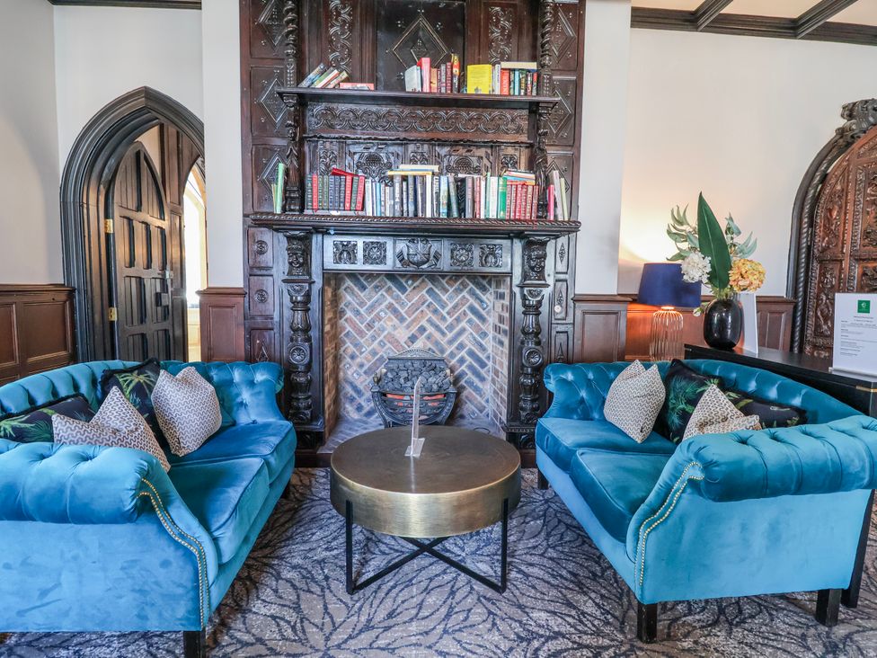 A living room with blue sofas and a bookshelf at Woodlands Gold (WO06) Ruthin