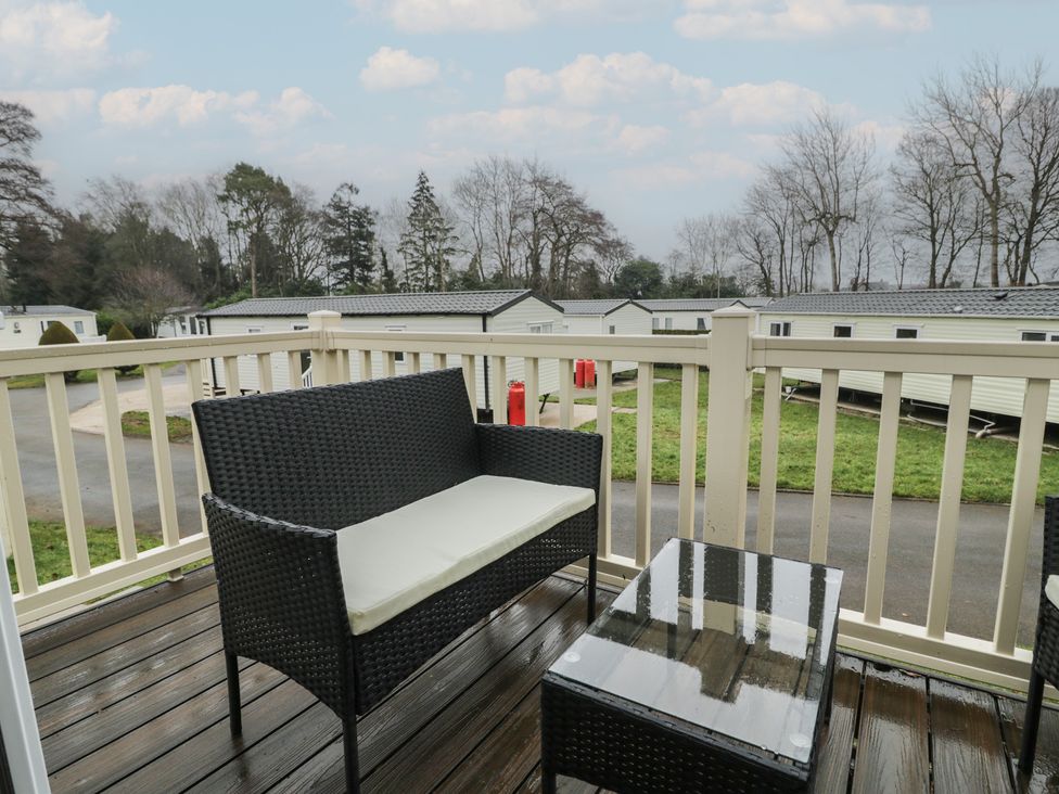 An outdoor seating area with a chair and table at Woodlands Platinum in Ruthin