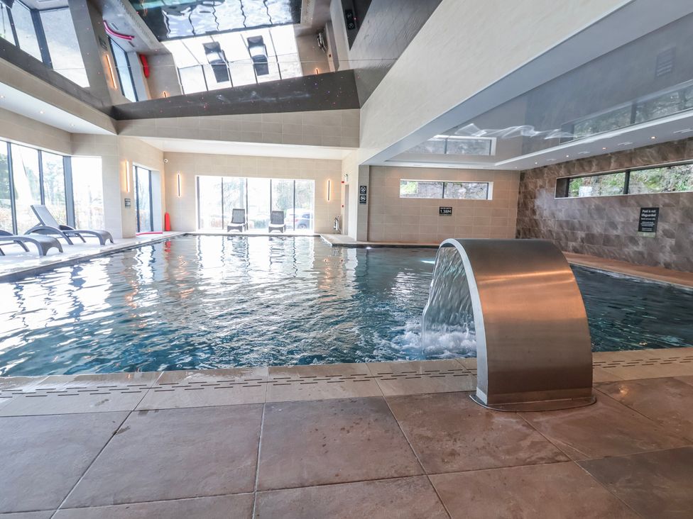 An indoor swimming pool with a fountain and lounge chairs at Woodlands Platinum (WO29) Ruthin