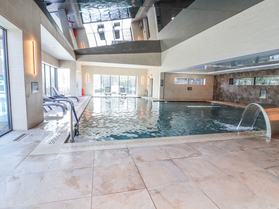 An indoor pool with seating and large windows at Woodlands Platinum (WO29) in Ruthin