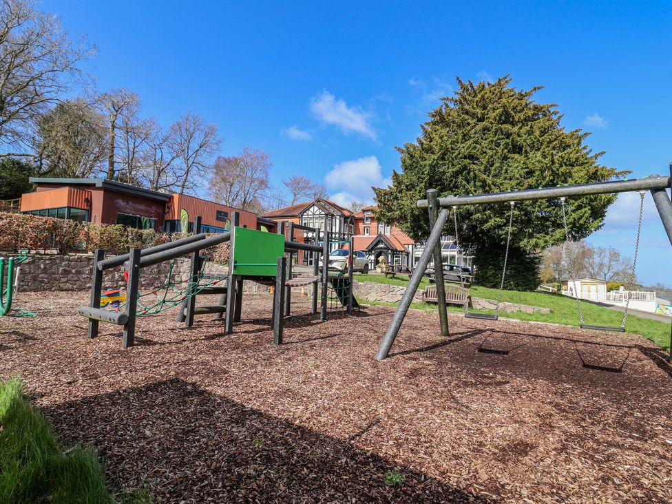 A playground with swings and climbing frame at Woodlands Platinum in Ruthin