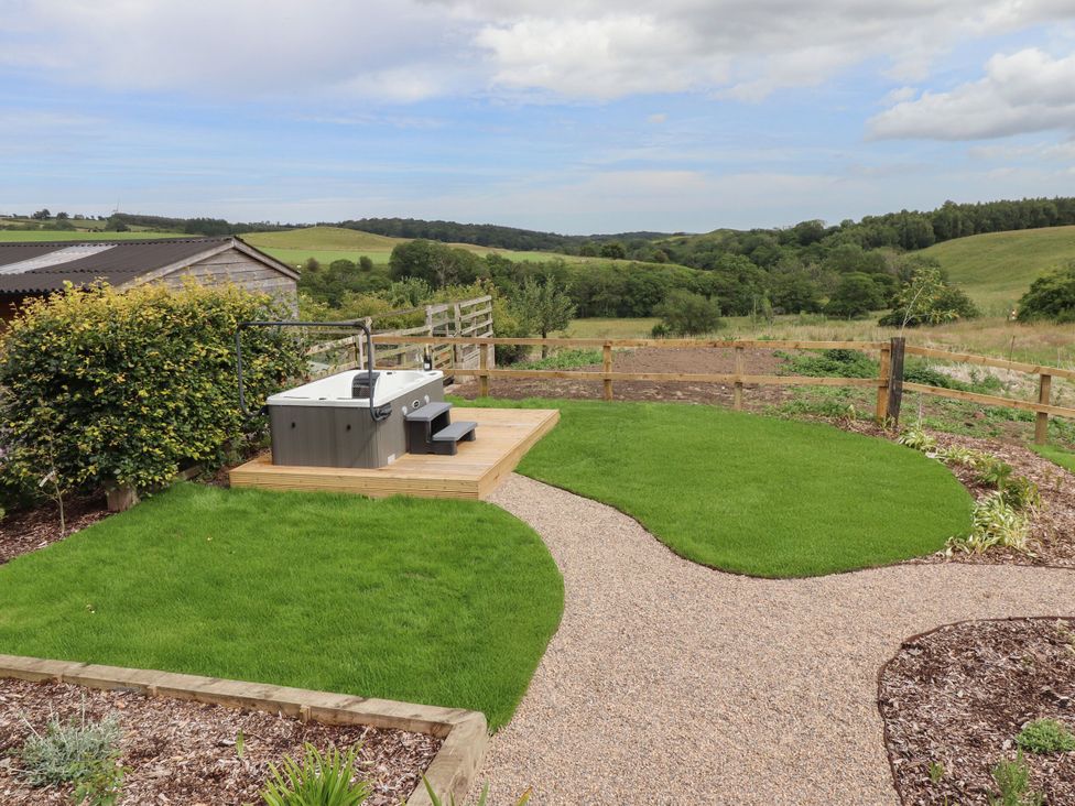 A garden with a hot tub and gravel path at Annex in Coldrife near Rothbury