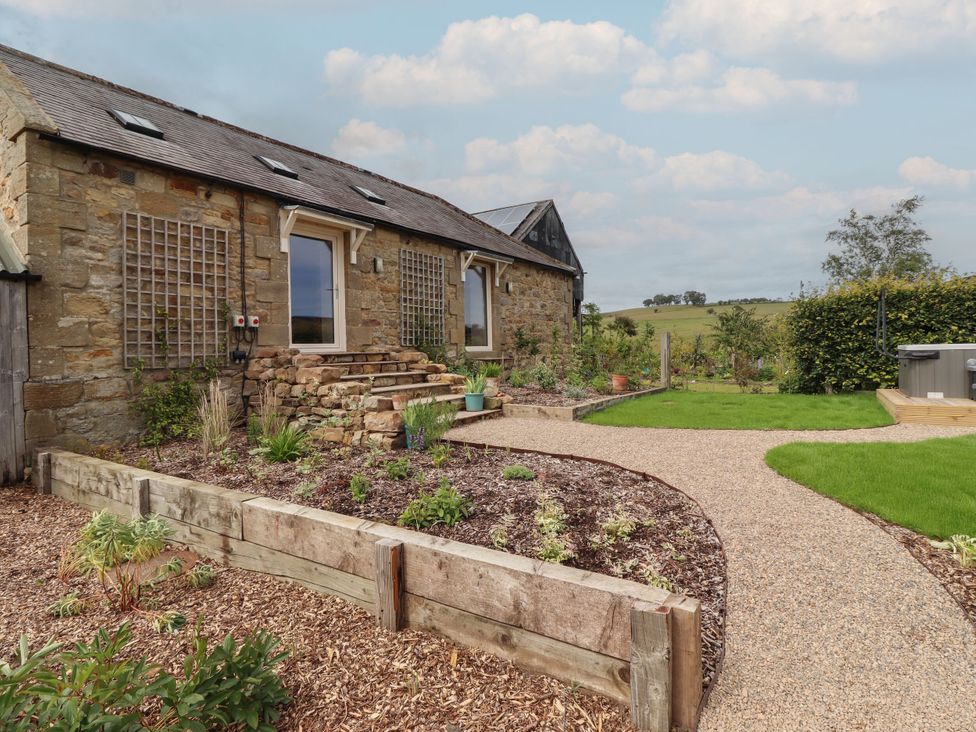 An outdoor view of a stone building with steps and garden at Annex in Coldrife near Rothbury