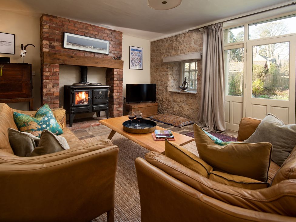A living room with a sofa, coffee table, and wood stove at The Old Coach House Eglingham near Alnwick