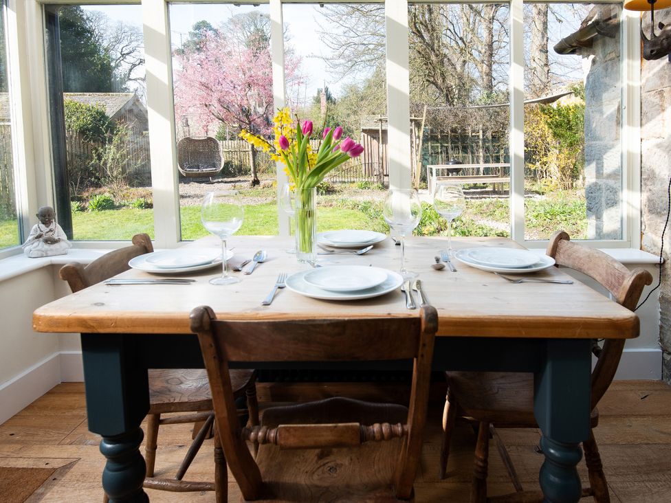 A dining room with a table set and flowers at The Old Coach House in Eglingham near Alnwick