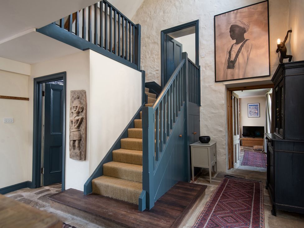 A hallway with a staircase and wall art at The Old Coach House in Eglingham near Alnwick