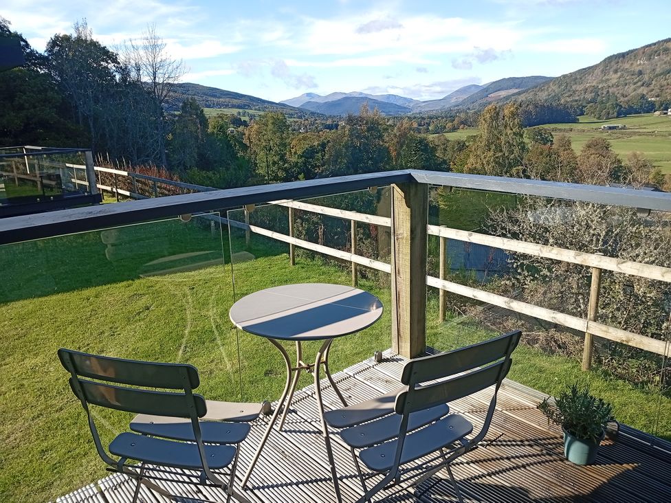 An outdoor seating area with a table and chairs overlooking the mountains at Dundarach in Aberfeldy