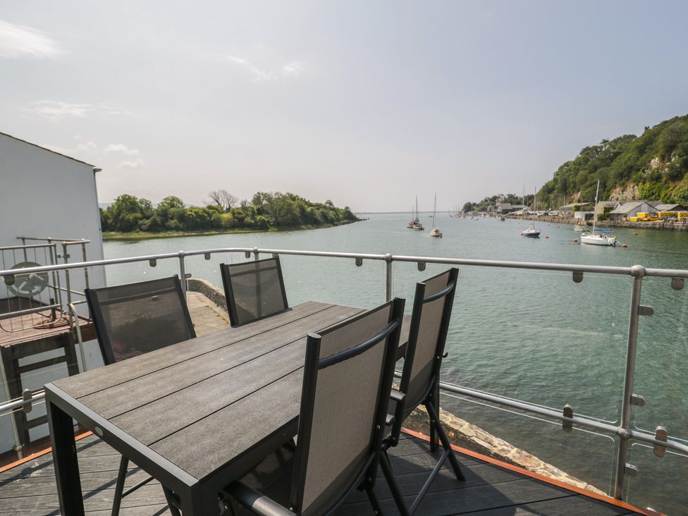 An outdoor seating area with a table and chairs overlooking the water at Seafarer's Haven in Porthmadog