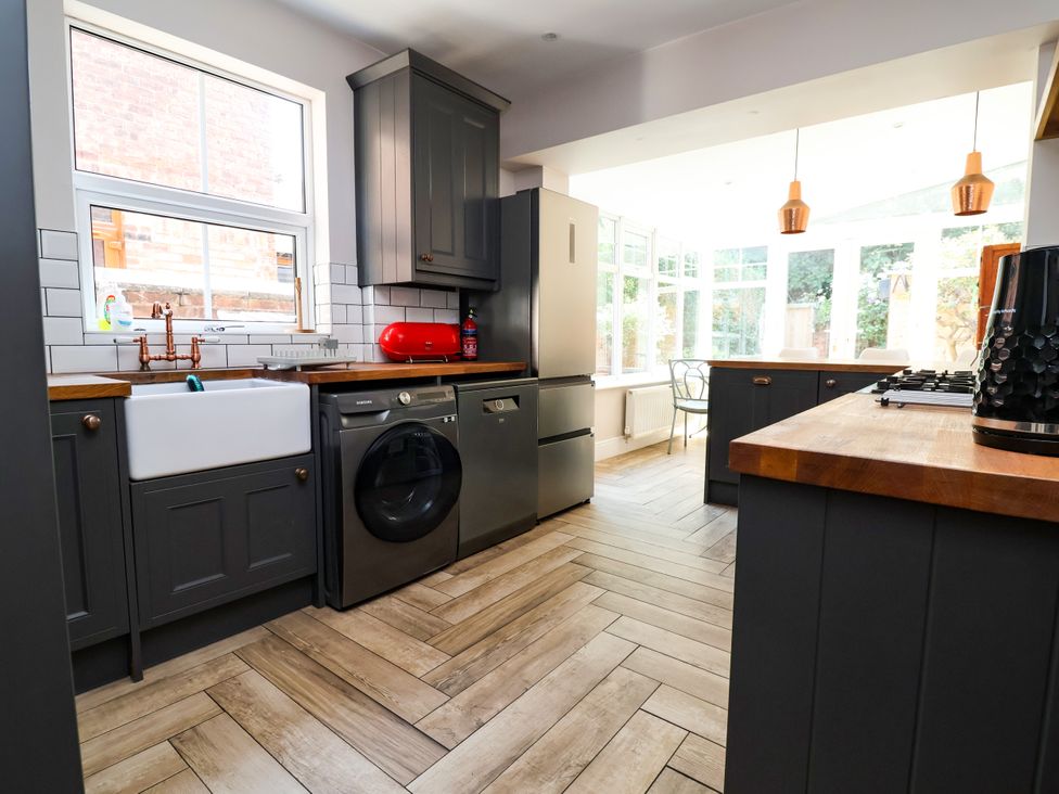 A kitchen with a sink, washing machine, and fridge at 45 Brook Lane Chester
