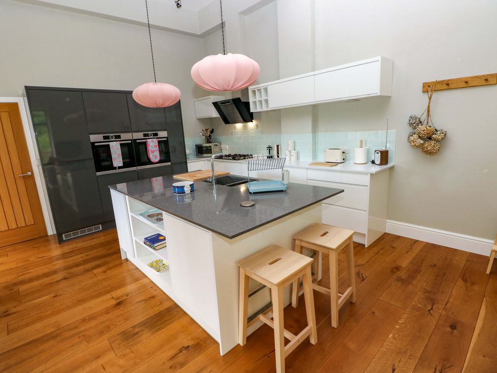 A kitchen with a countertop and stools at The Old Creamery in Ffairfach