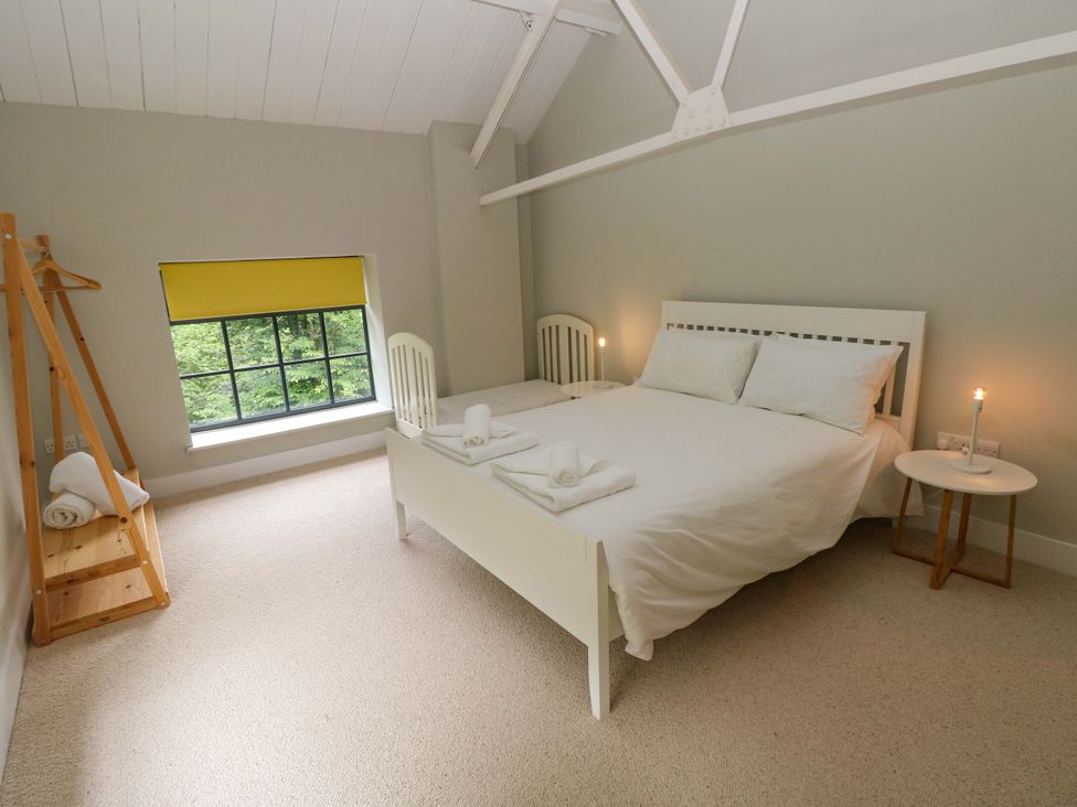 A bedroom with a bed and window at The Old Creamery in Ffairfach