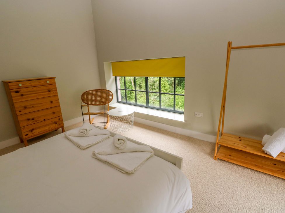 A bedroom with a bed and wooden furniture at The Old Creamery in Ffairfach
