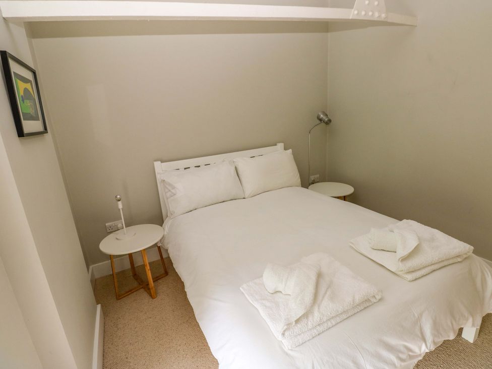 A bedroom with a bed, bedside table, and lamp at The Old Creamery in Ffairfach