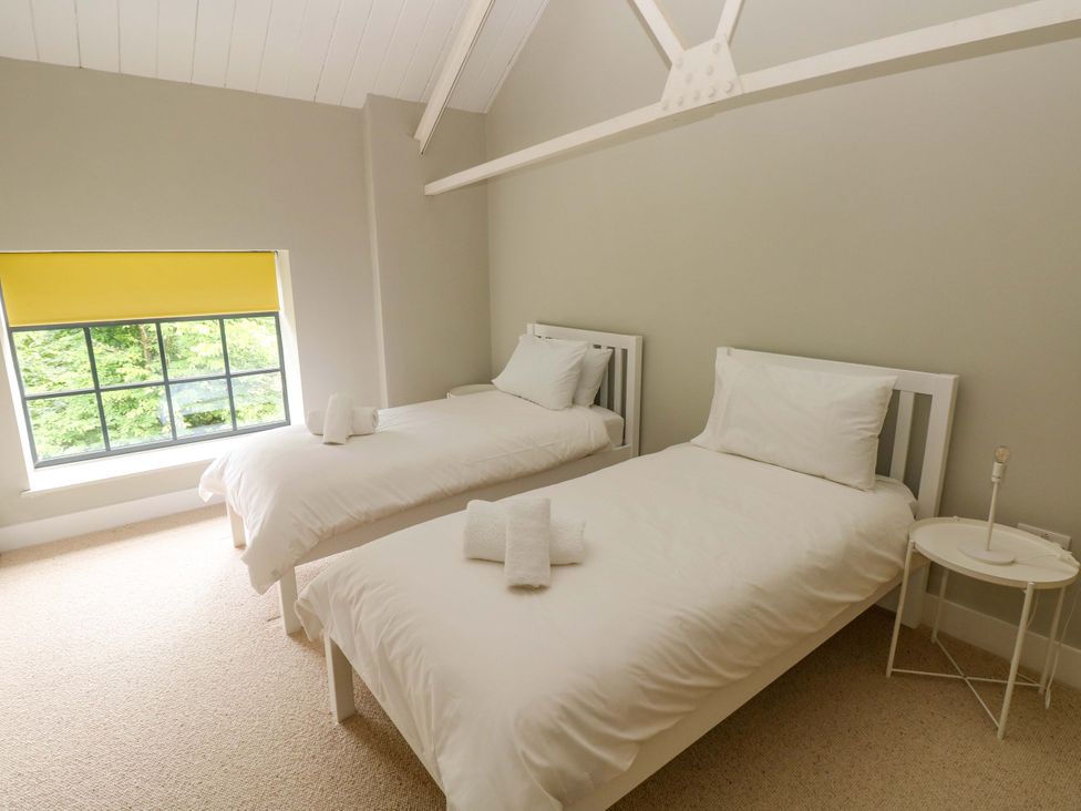 A bedroom with two single beds and a window at The Old Creamery in Ffairfach