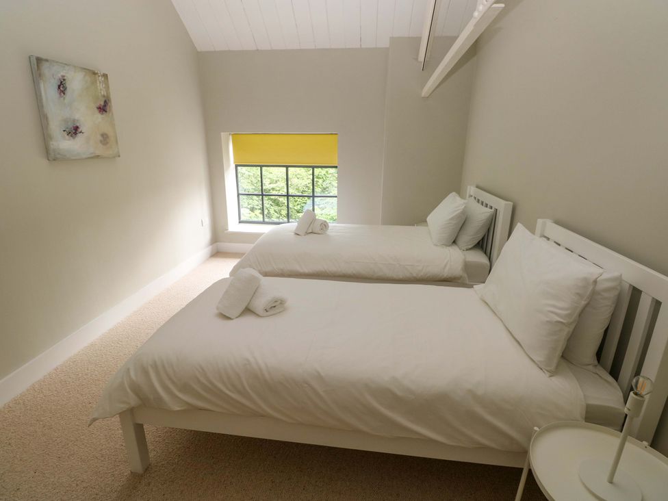 A bedroom with two beds and a window at The Old Creamery in Ffairfach