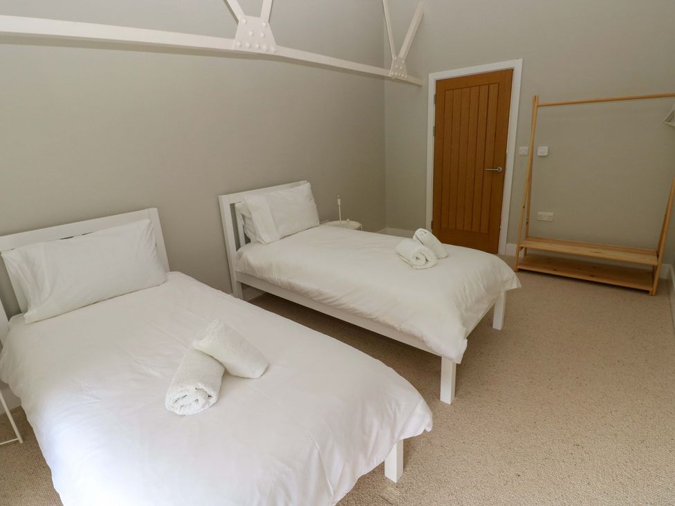 A bedroom with two single beds and a clothing rack at The Old Creamery in Ffairfach