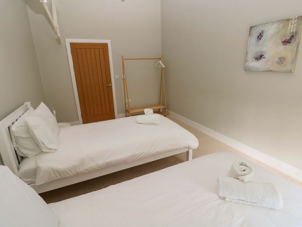A bedroom with two beds and a wall portrait at The Old Creamery in Ffairfach
