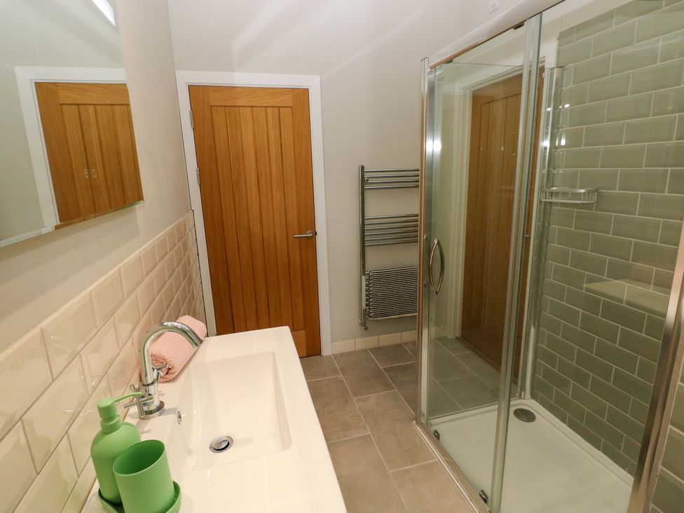 A bathroom with a sink, shower, and towel rack at The Old Creamery in Ffairfach