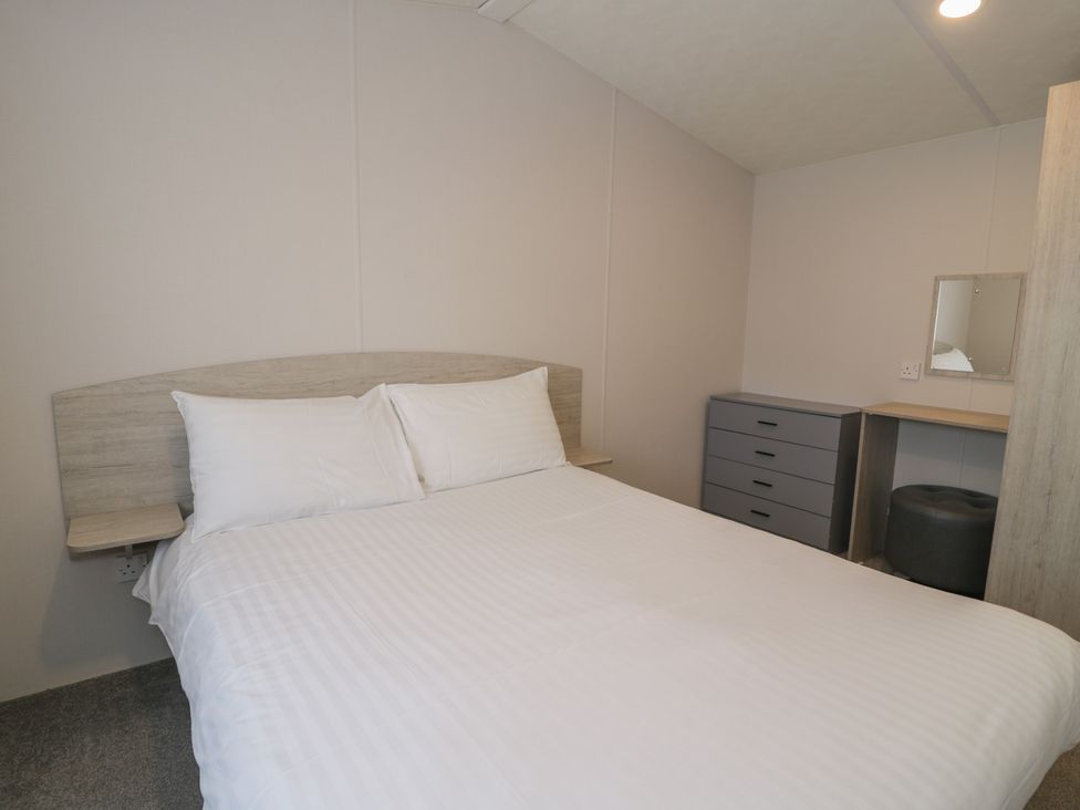 A bedroom with a bed and a desk with a mirror at Gold Caravan (316) Talybont