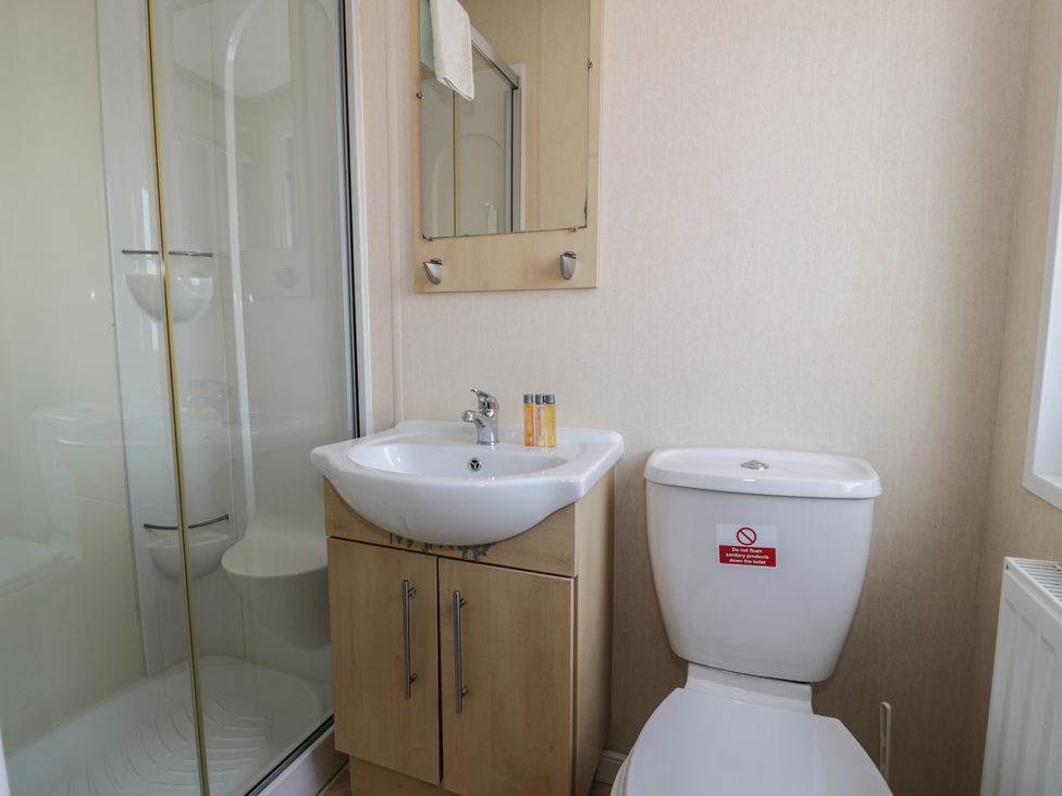 A bathroom with a sink, toilet, shower, and mirror at Gold Lodge (201) Talybont