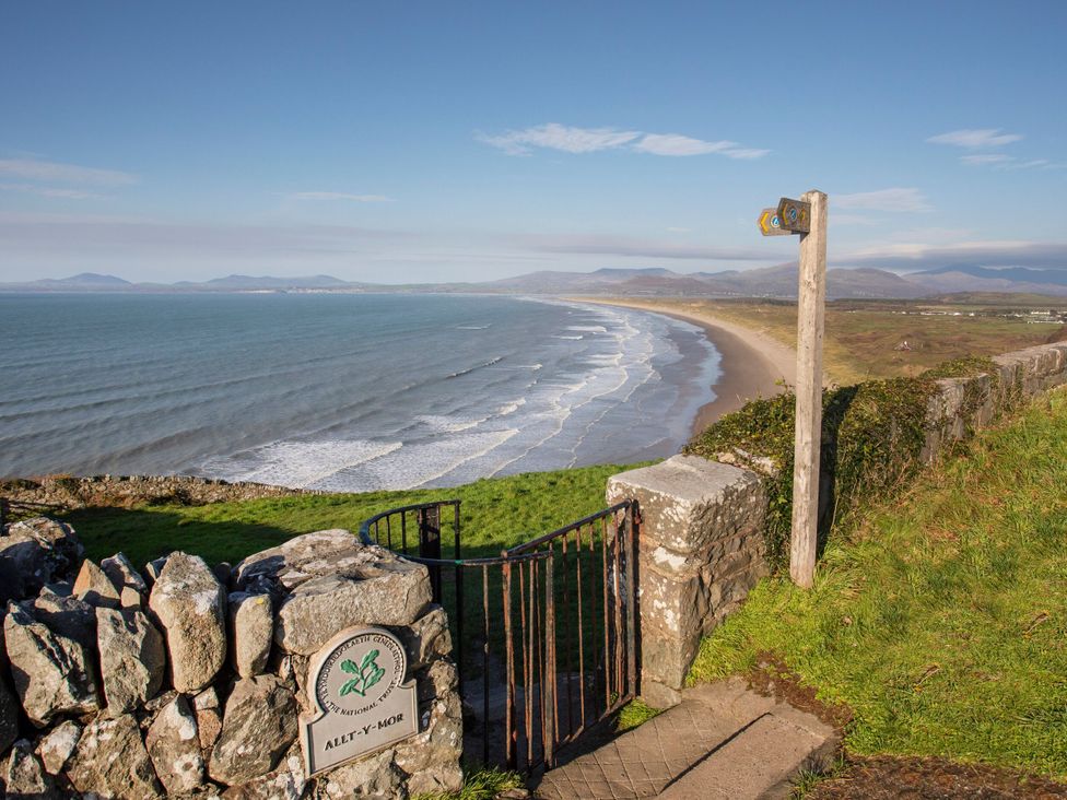 A beach view with a path and signpost at Alet-y-Mor in Talybont